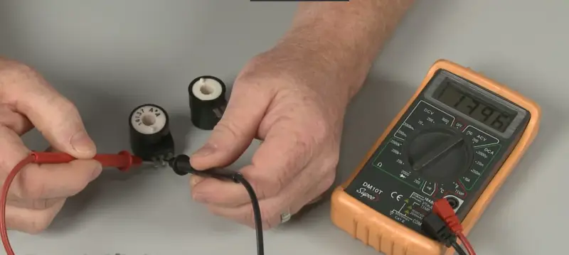 Technician testing LG dryer gas valve solenoid coil with multimeter